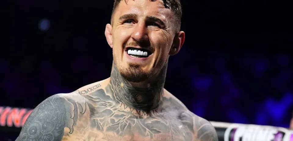 Boxer smiling with tattoos and mouthguard in ring