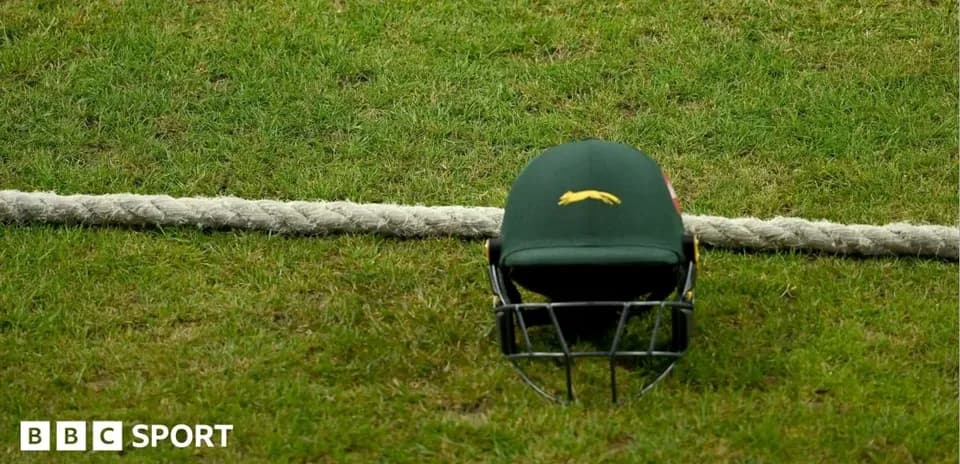 Cricket helmet resting on grass near boundary rope