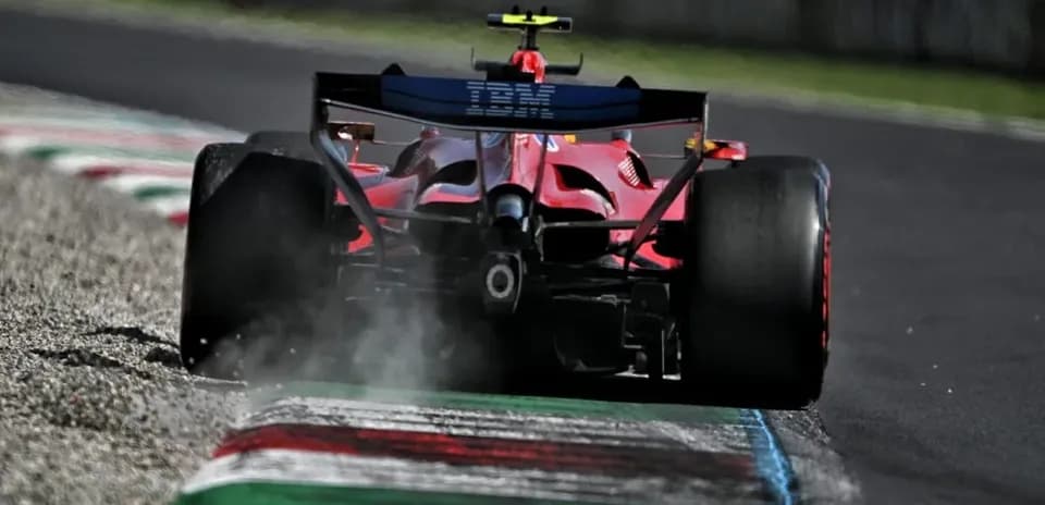 Red Formula 1 car driving on track with smoke