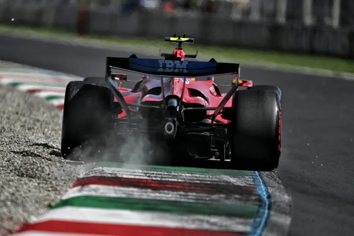 Red Formula 1 car driving on track with smoke