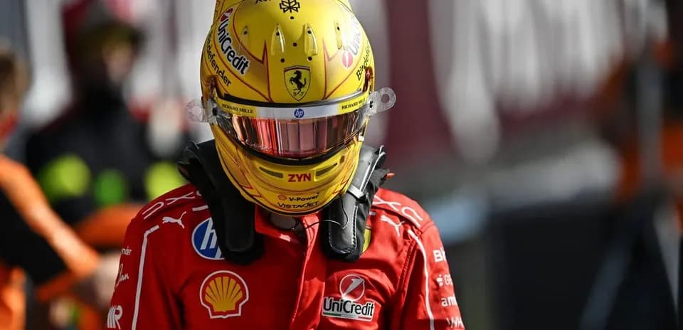 Driver in red Ferrari suit wearing helmet in pit area