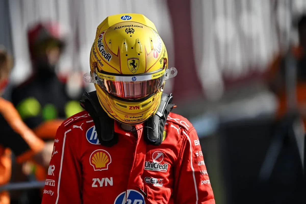 Driver in red Ferrari suit wearing helmet in pit area