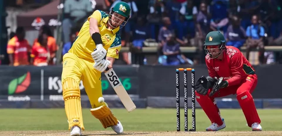 Batsman hitting ball while wicketkeeper crouches