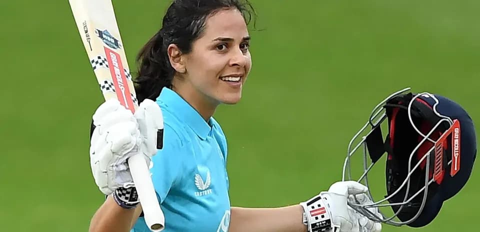 Cricketer celebrating with bat and helmet raised