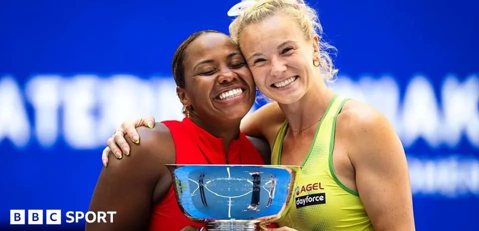 Two tennis players holding a trophy together