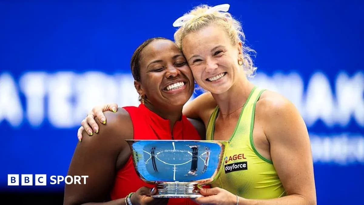 Two tennis players holding a trophy together