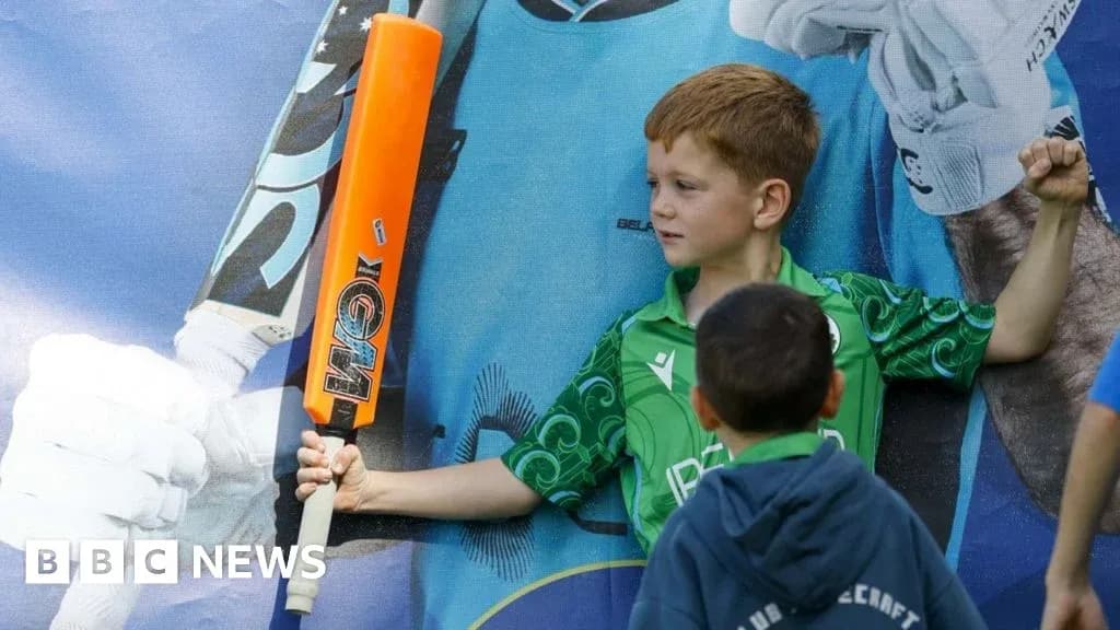 Child posing with cricket bat against mural backdrop