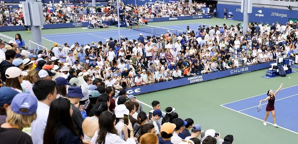Crowd watching tennis match at outdoor stadium