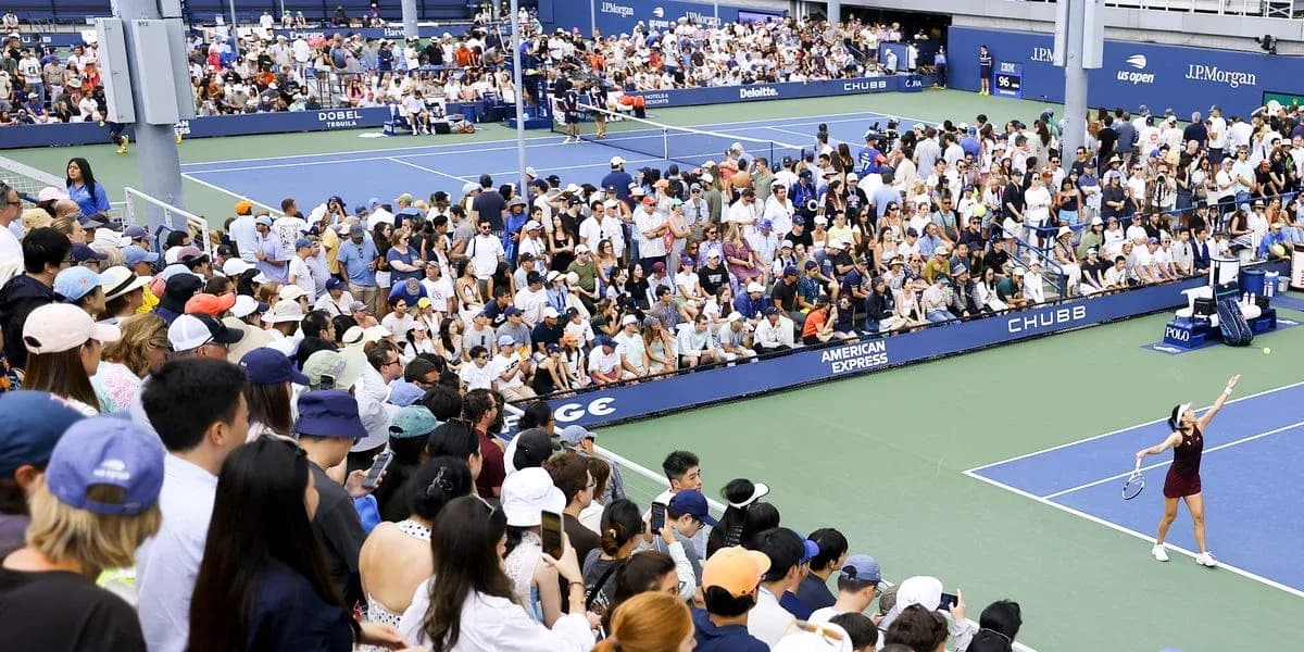 Crowd watching tennis match at outdoor stadium