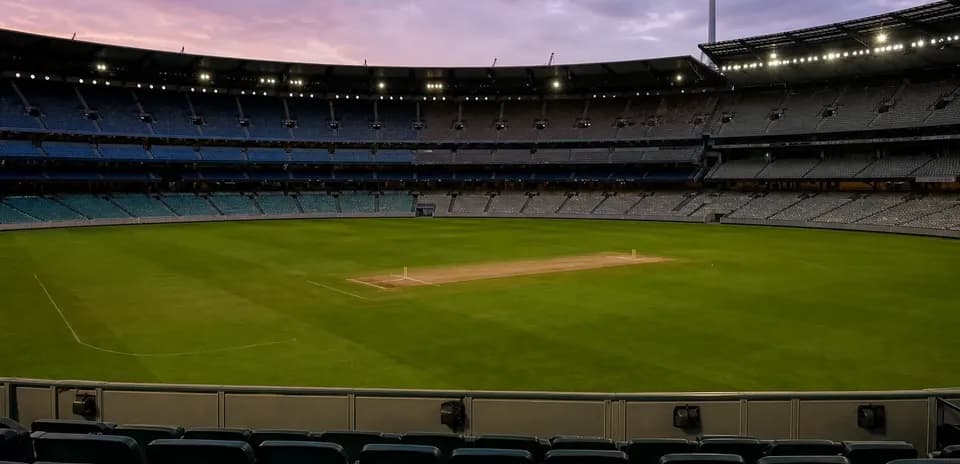 Empty cricket stadium with pitch at twilight
