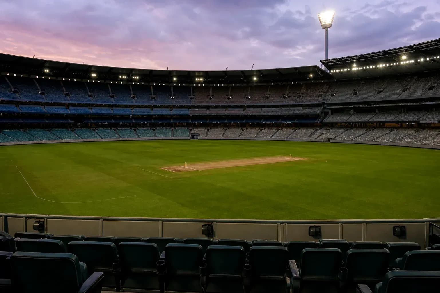 Empty cricket stadium with pitch at twilight