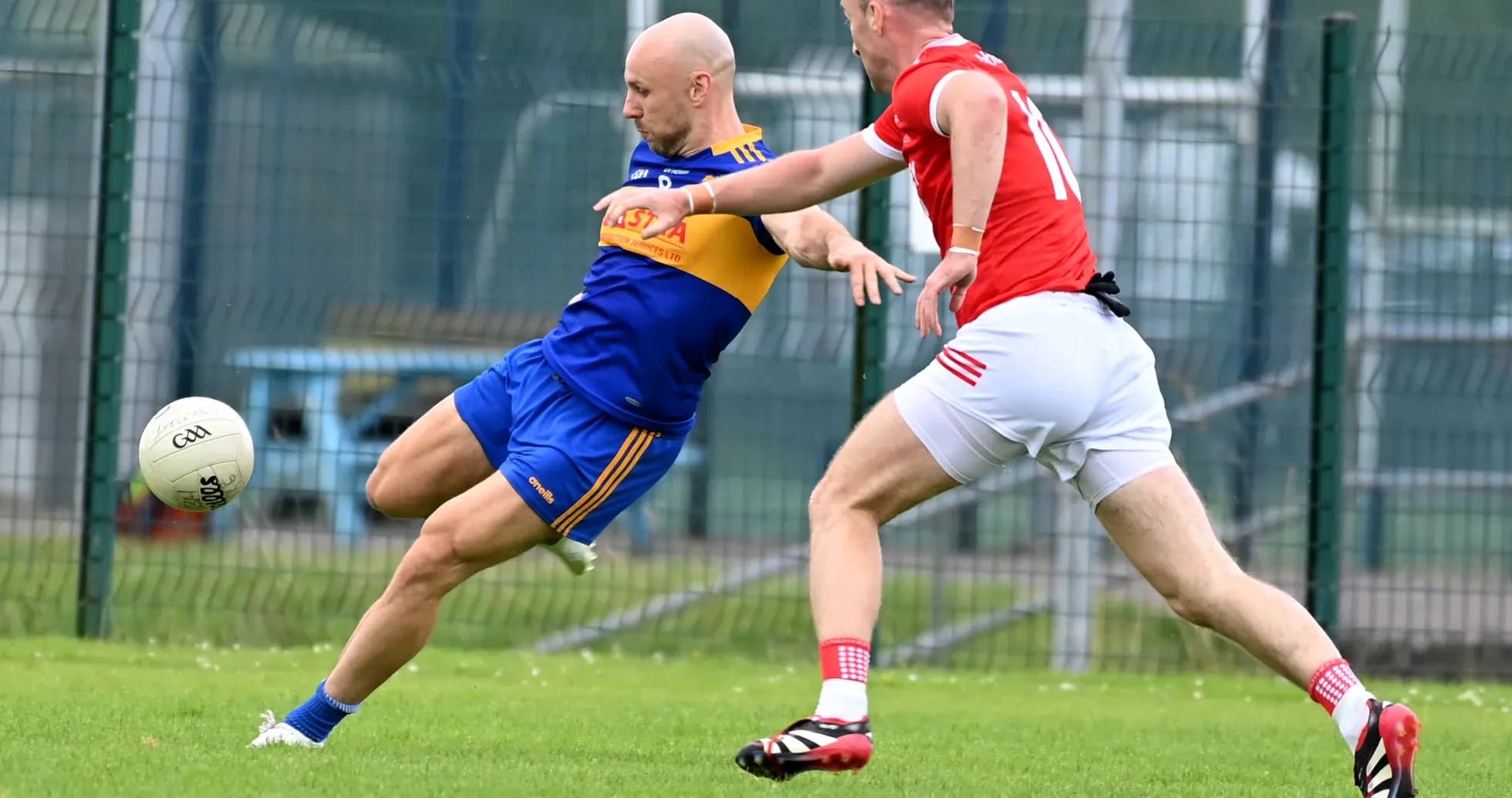 Player kicking ball while being tackled by opponent