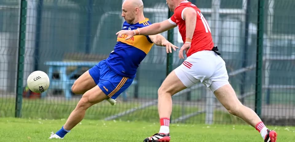 Player kicking ball while being tackled by opponent