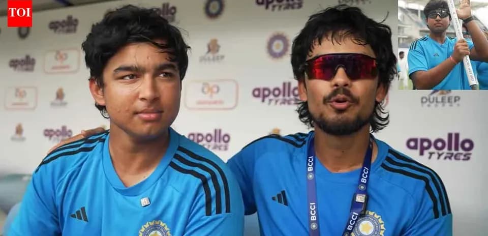 Two players seated at press conference table wearing blue jerseys