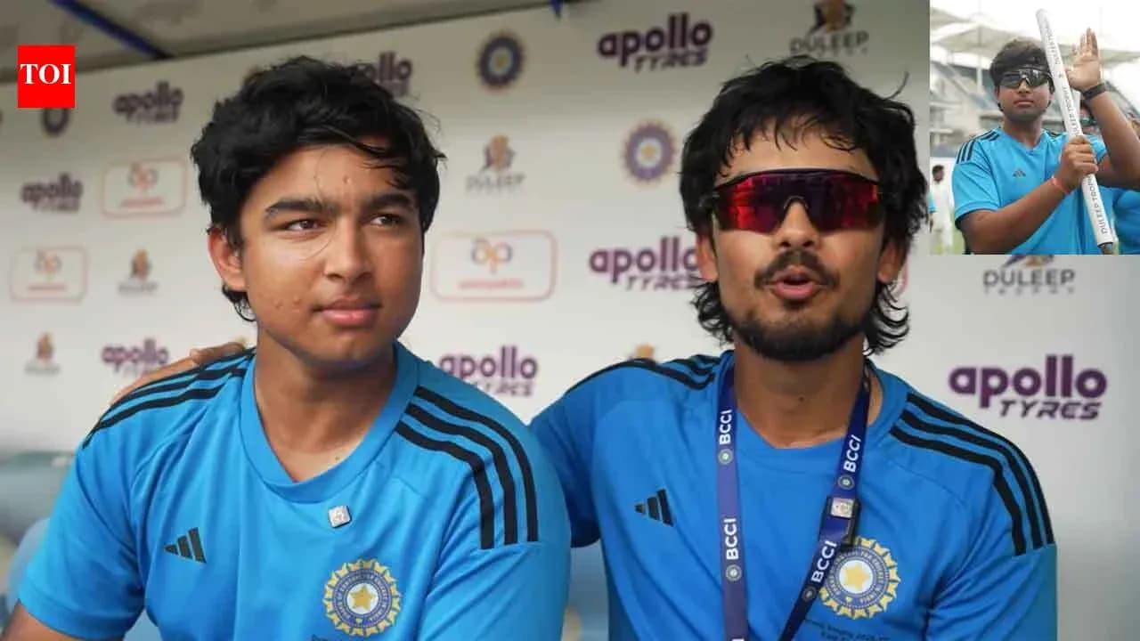 Two players seated at press conference table wearing blue jerseys