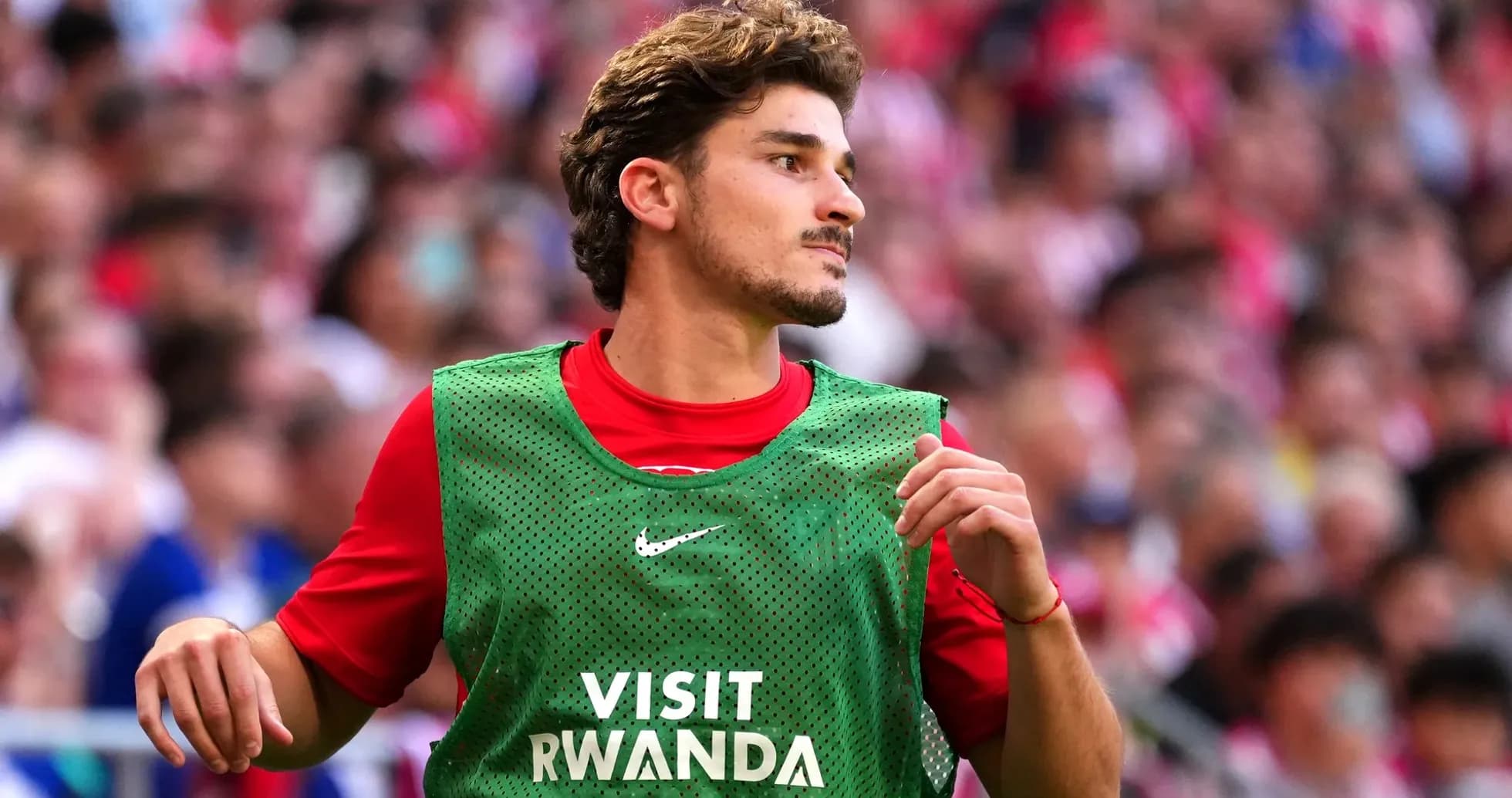 Player in green training bib on sidelines