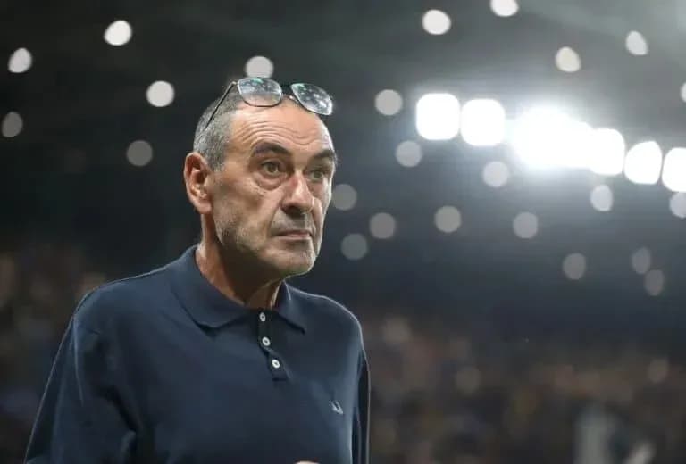 Coach observing match from sidelines with glasses