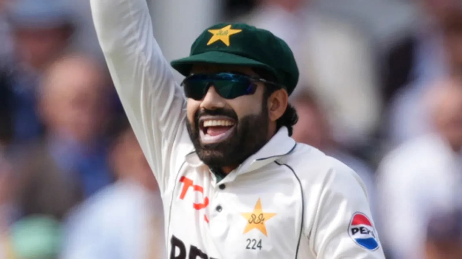 Cricketer celebrating with raised arm on field