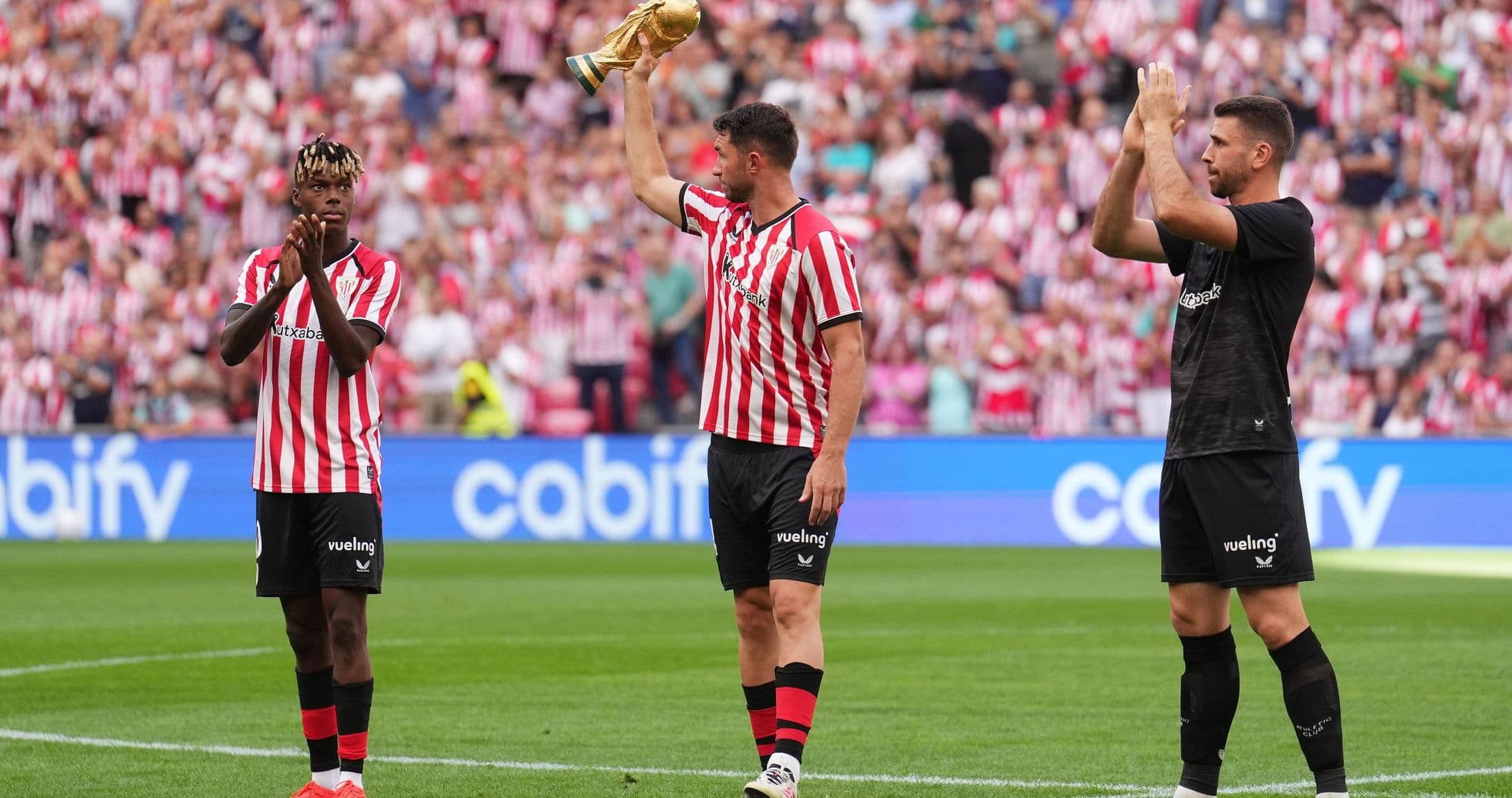 Players celebrating with trophy in front of fans