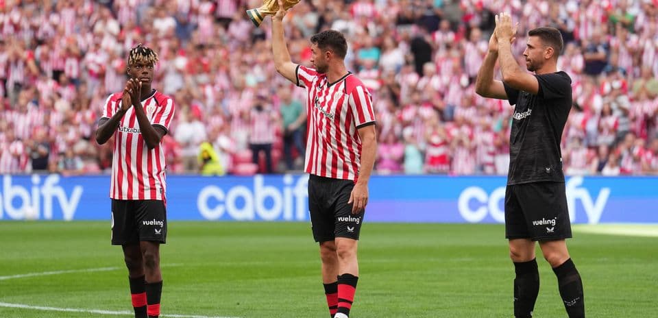 Players celebrating with trophy in front of fans