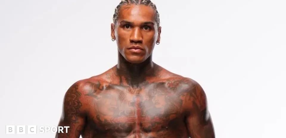 Muscular athlete with tattoos posing against white background