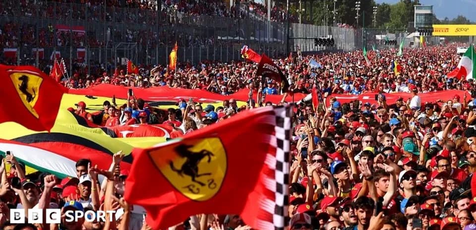 Crowd of fans waving Ferrari flags at race