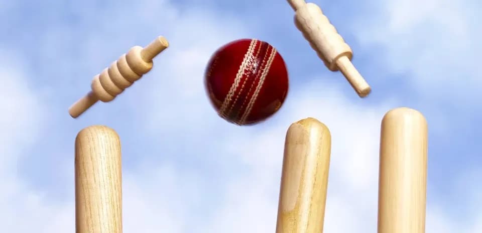 Cricket ball hitting stumps with bails above