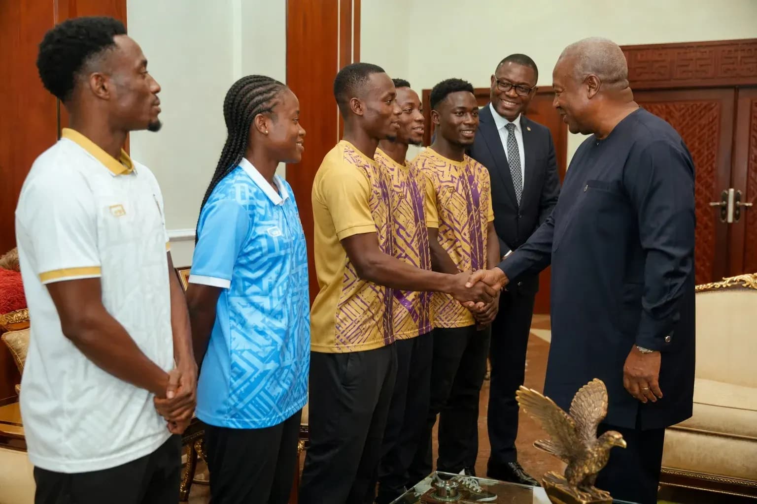 Athletes shaking hands with dignitaries in meeting