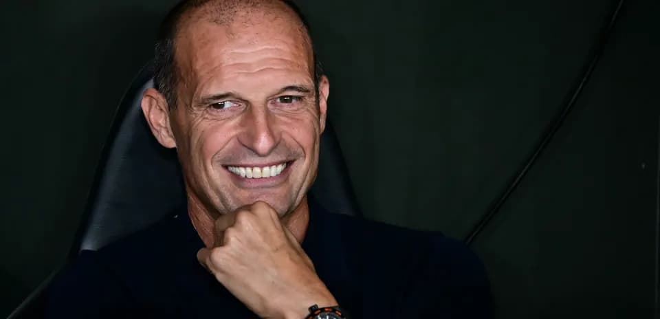 Smiling coach seated with hand on chin