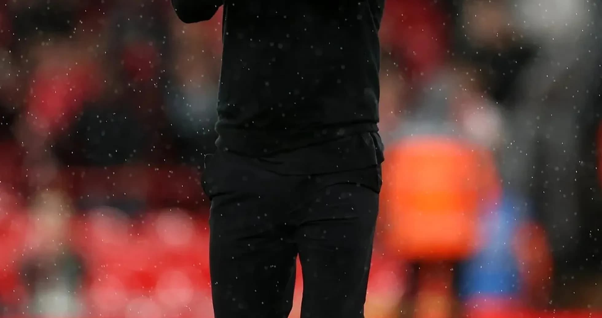 Manager applauding the crowd during rainy match