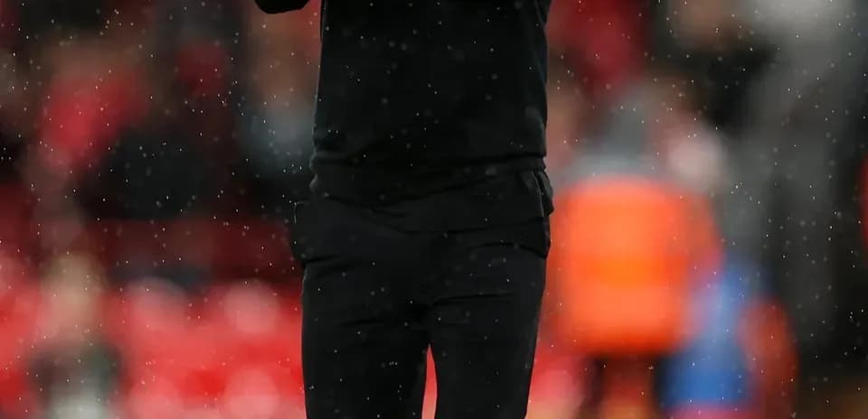 Manager applauding the crowd during rainy match
