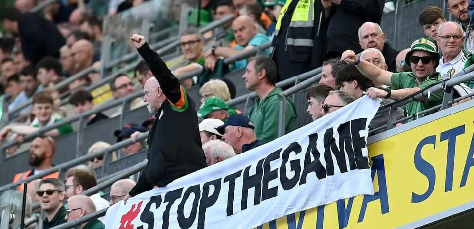 Fans holding a '#STOPTHEGAME' banner in stadium