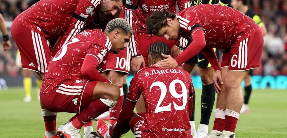 Liverpool players supporting teammate on the ground