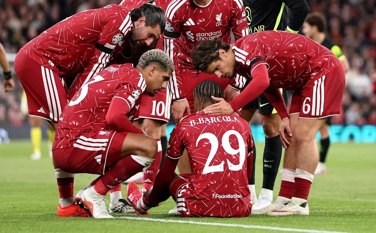 Liverpool players supporting teammate on the ground