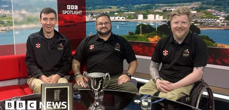 Three men sitting with trophy on news set