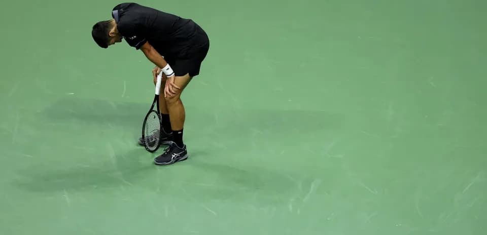 Tennis player bending over on green court