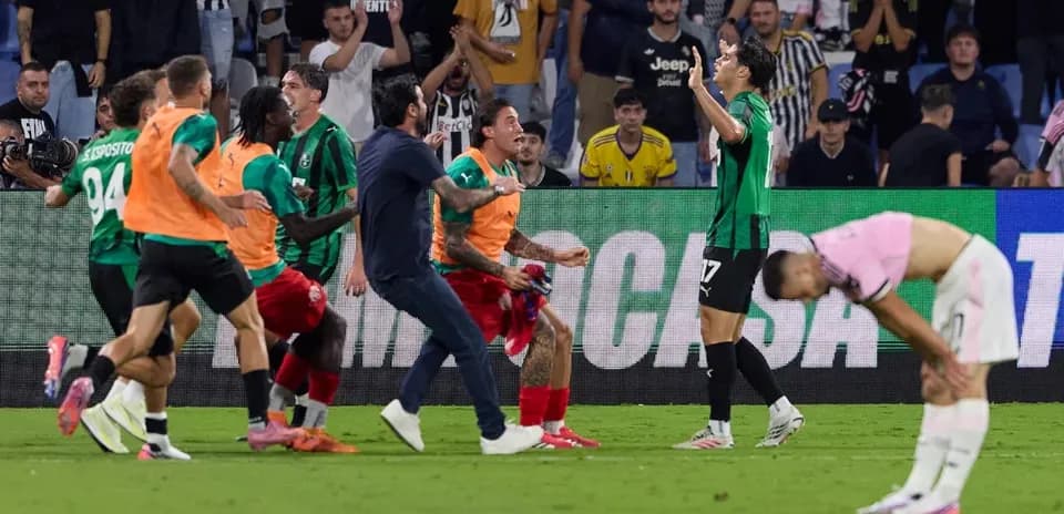 Players celebrating a goal with fans in the background