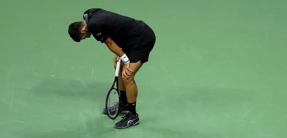 Tennis player bending over on the court