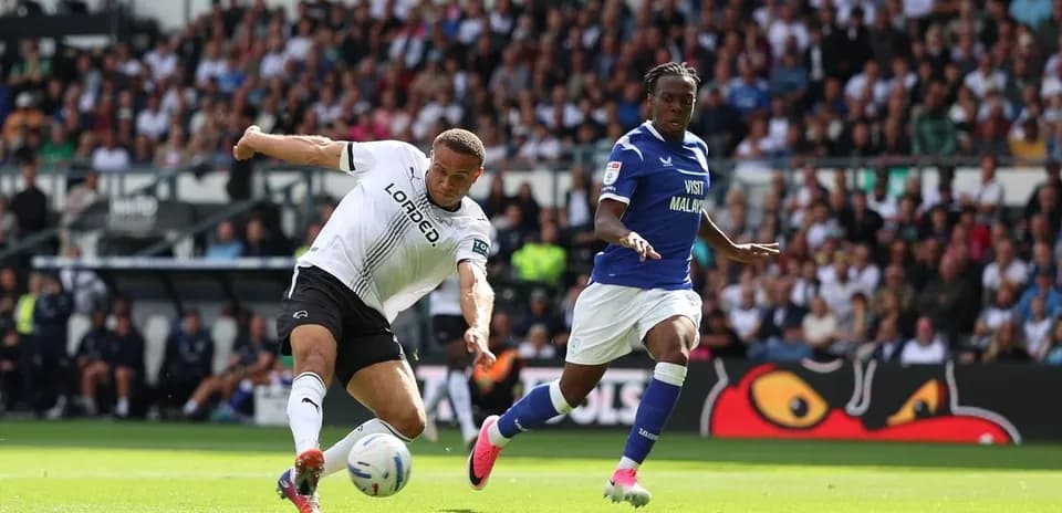 Player kicking ball while another defends during match