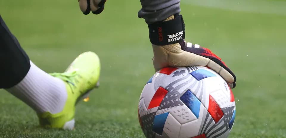 Goalkeeper placing hand on soccer ball before kick