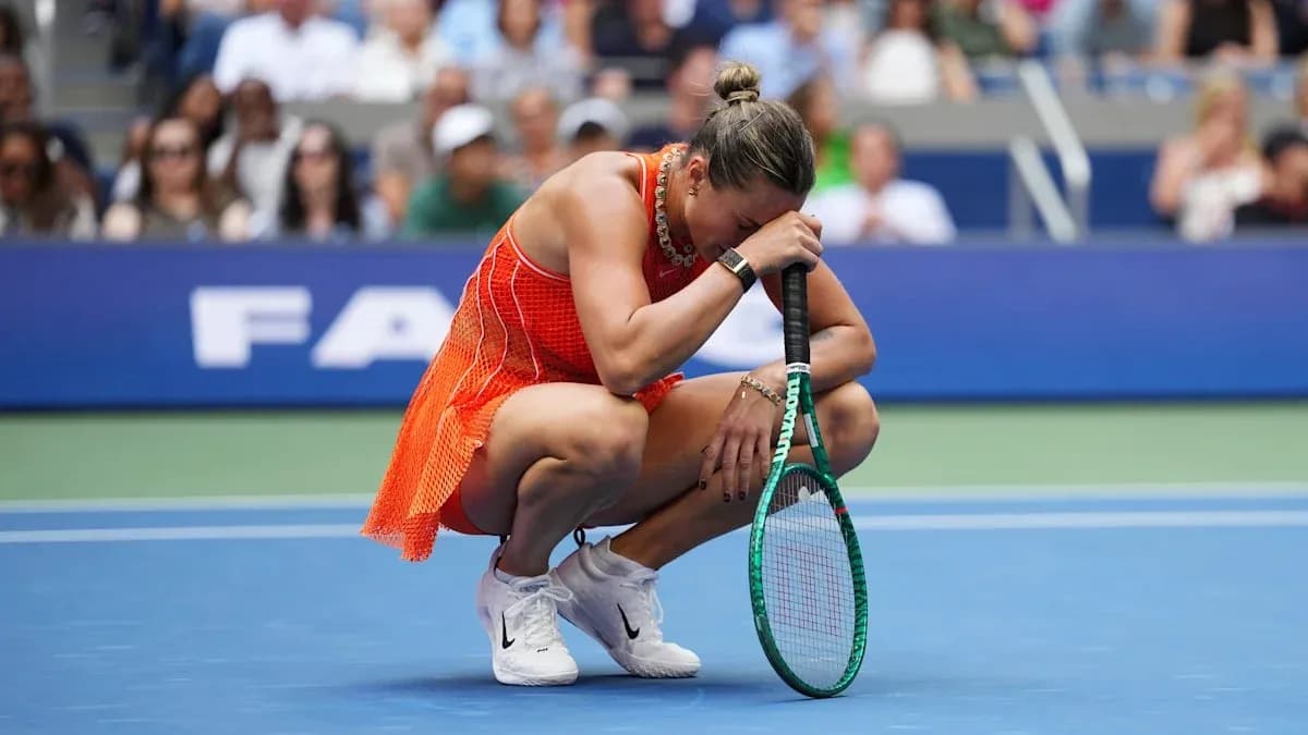 Player kneeling on court holding racket, crowd visible