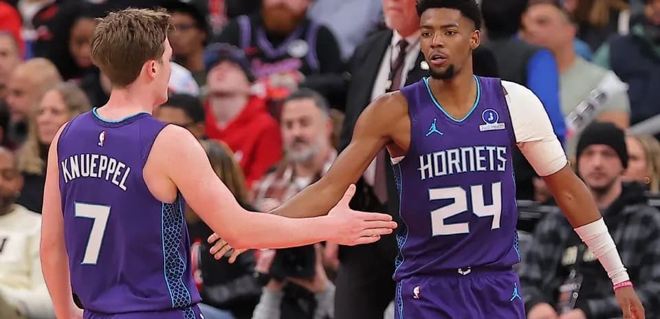 Two Hornets players exchanging a handshake during game