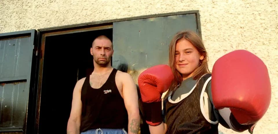 Young girl in boxing gloves with trainer outside gym