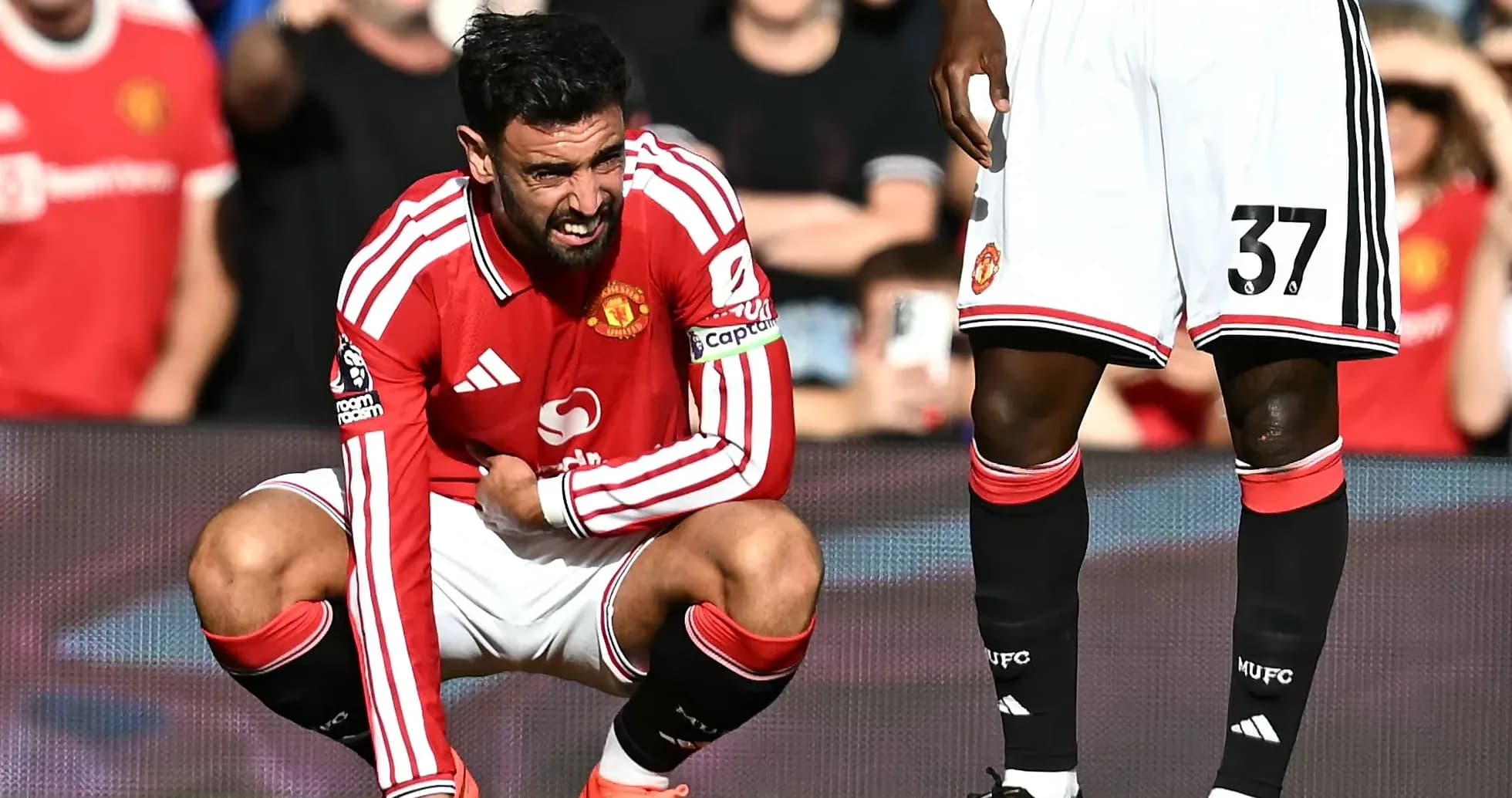 Bruno Fernandes crouching on pitch, holding his leg