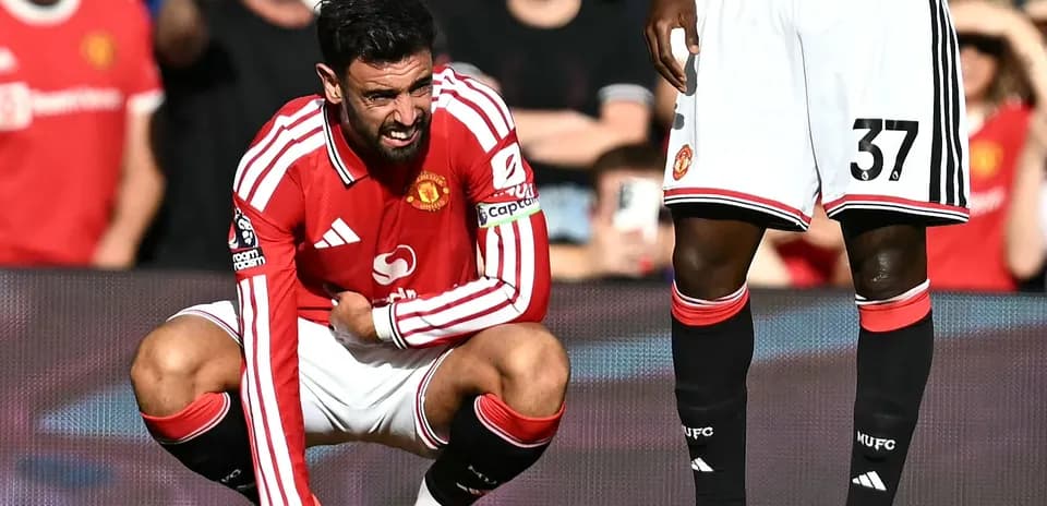Bruno Fernandes crouching on pitch, holding his leg