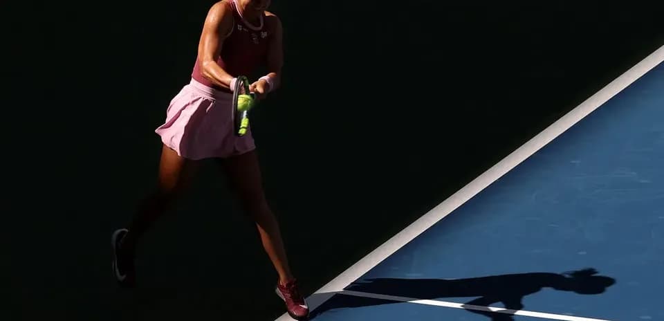 Player hitting tennis ball on court with shadow