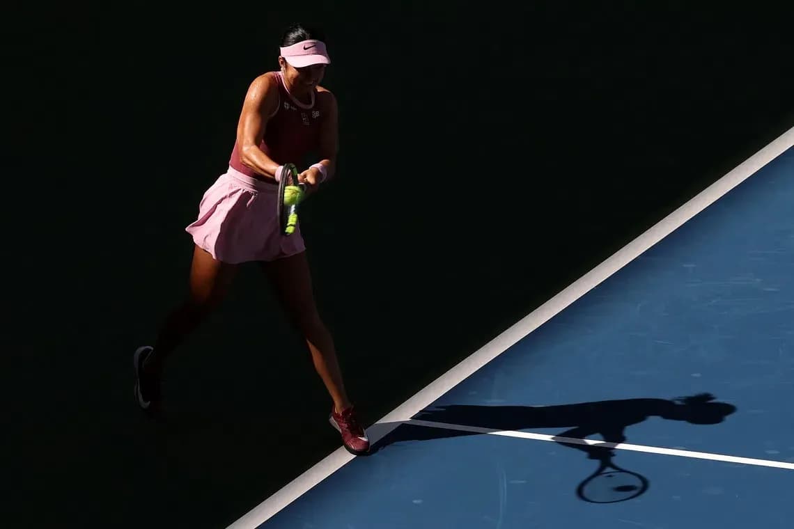 Player hitting tennis ball on court with shadow