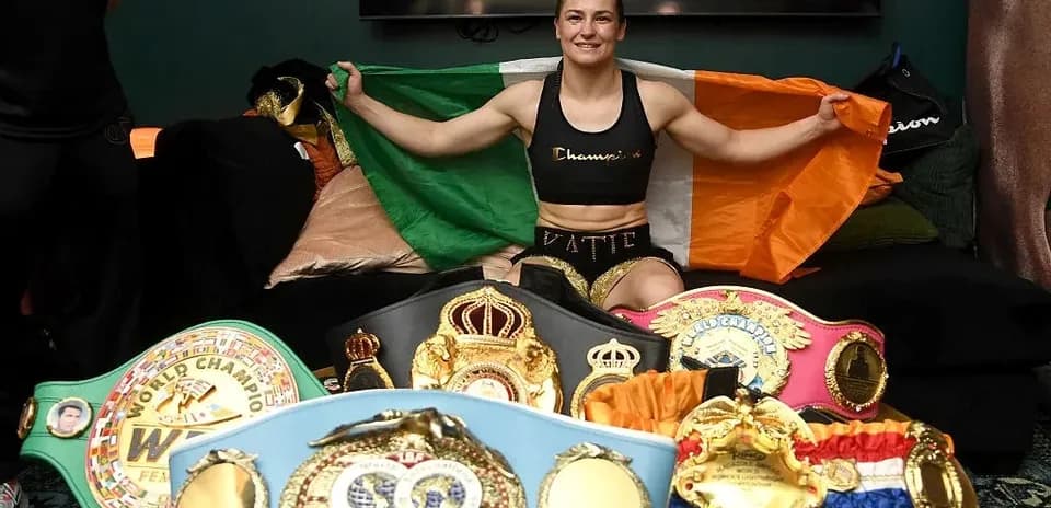 Female boxer holding Irish flag with championship belts