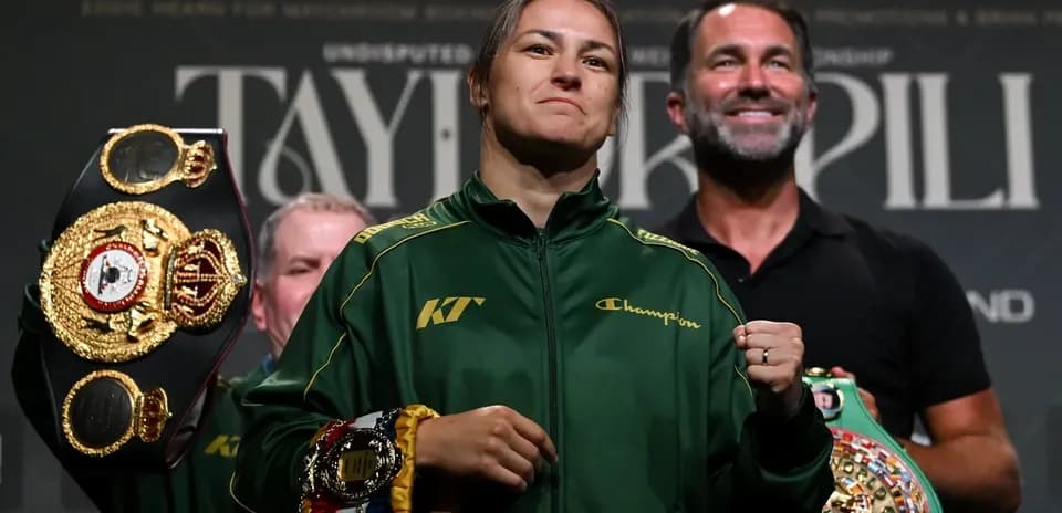 Female boxer holding championship belts at press event