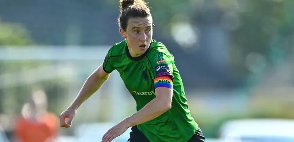 Female soccer player in green kit with captain's armband